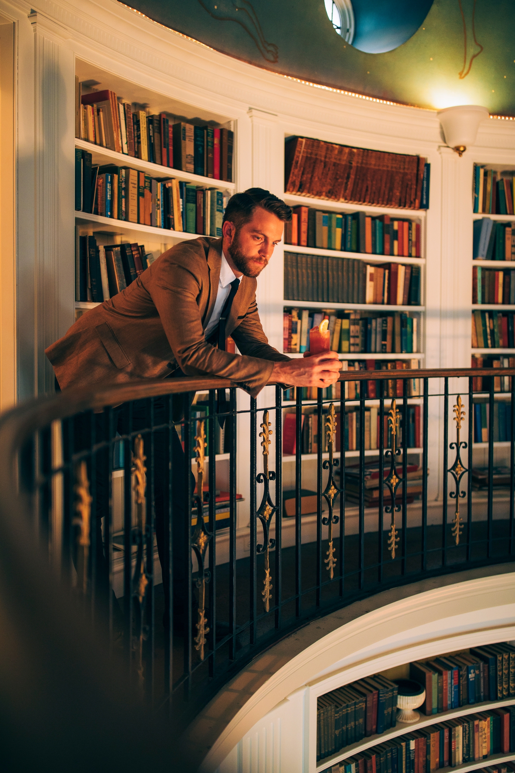 man leaning on a bannister in the library