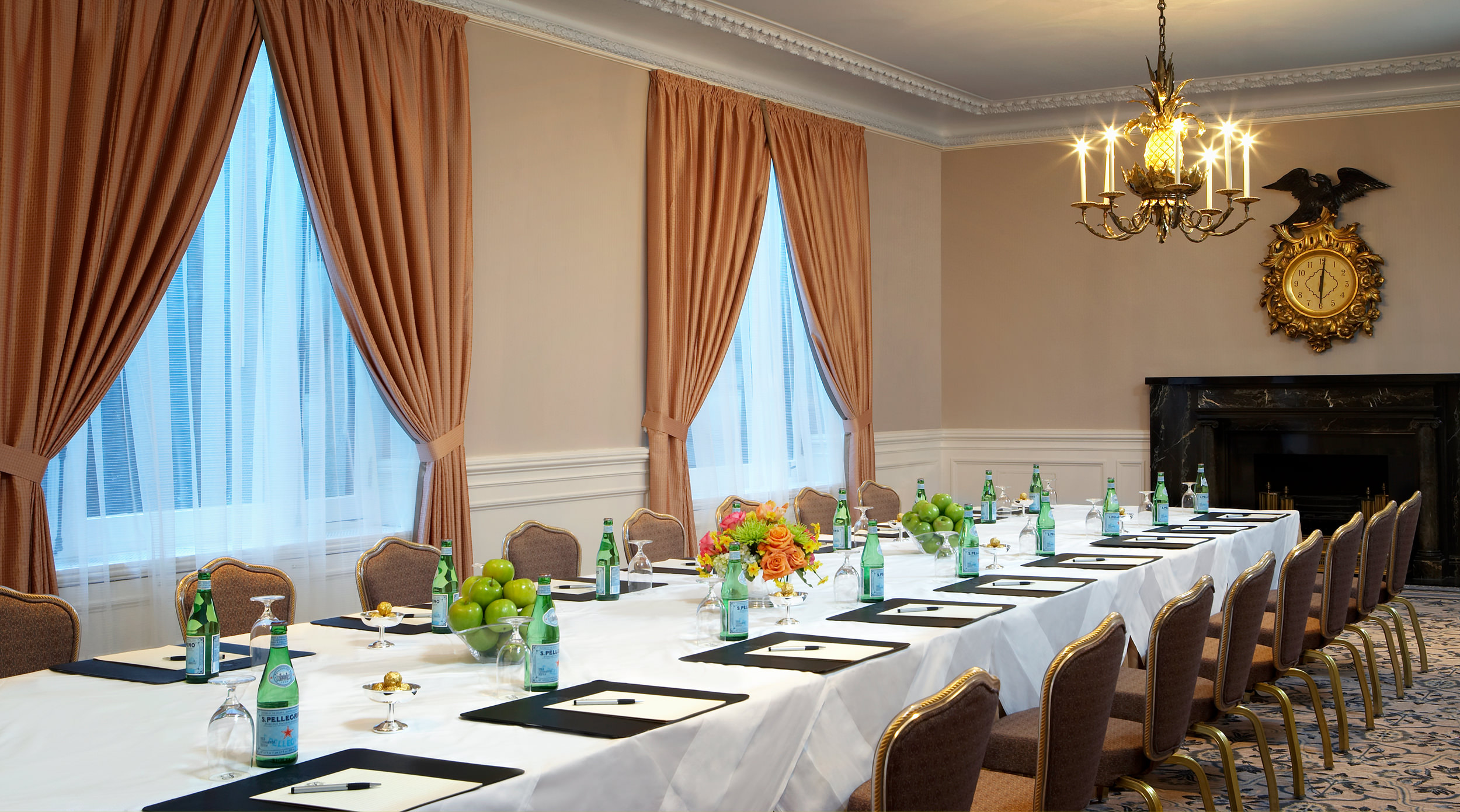 Sparkling water and fruit are set on a long white tablecloth table