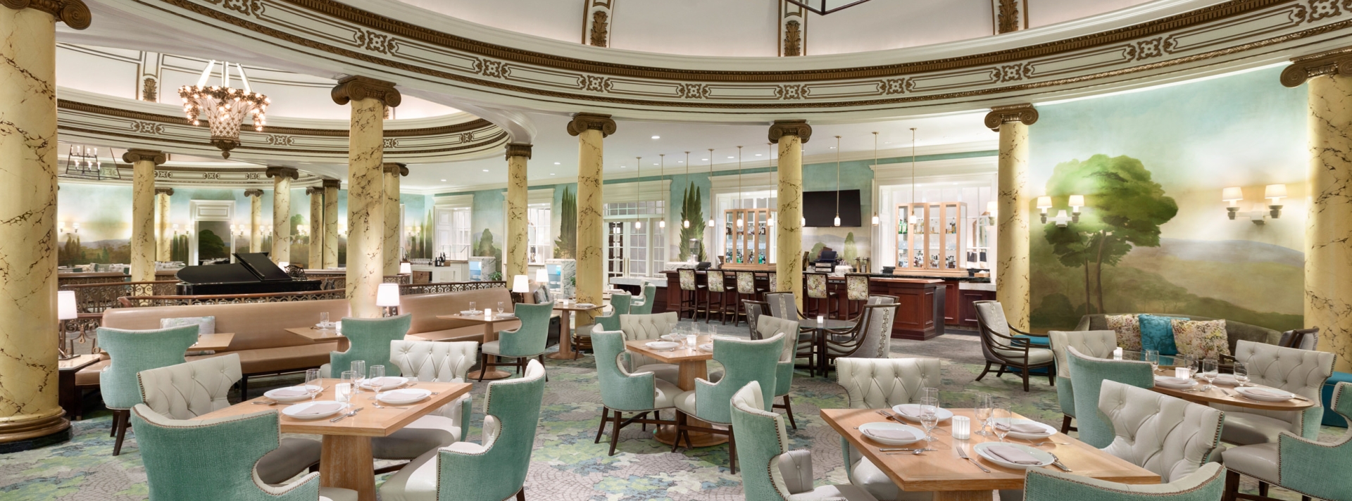 The dining room is filled with pale green chairs and square wood-grain tables